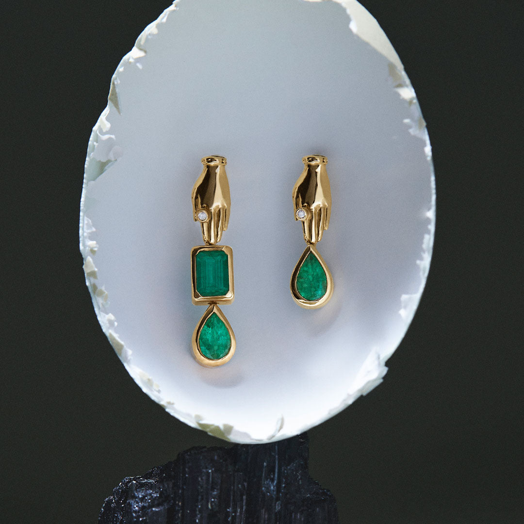 Asymmetrical 18k gold hand earrings adorned with emeralds and diamonds