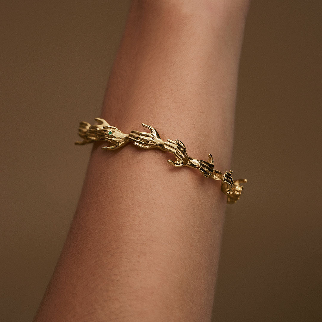 Model wearing hand-shaped bracelet in sterling silver chain with 18k gold plating
