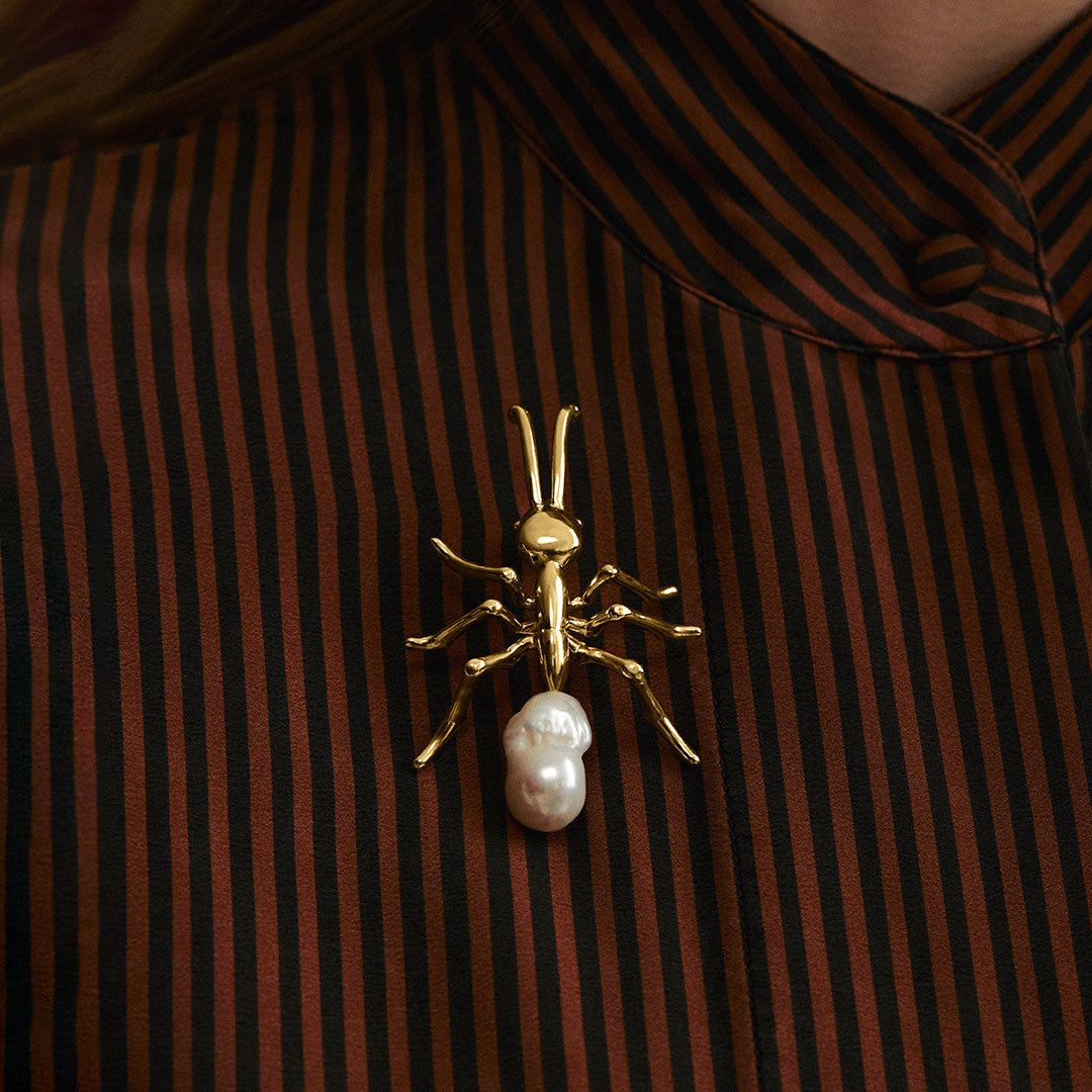 Model wearing large ant brooch in sterling silver with 18k gold plating and baroque pearl