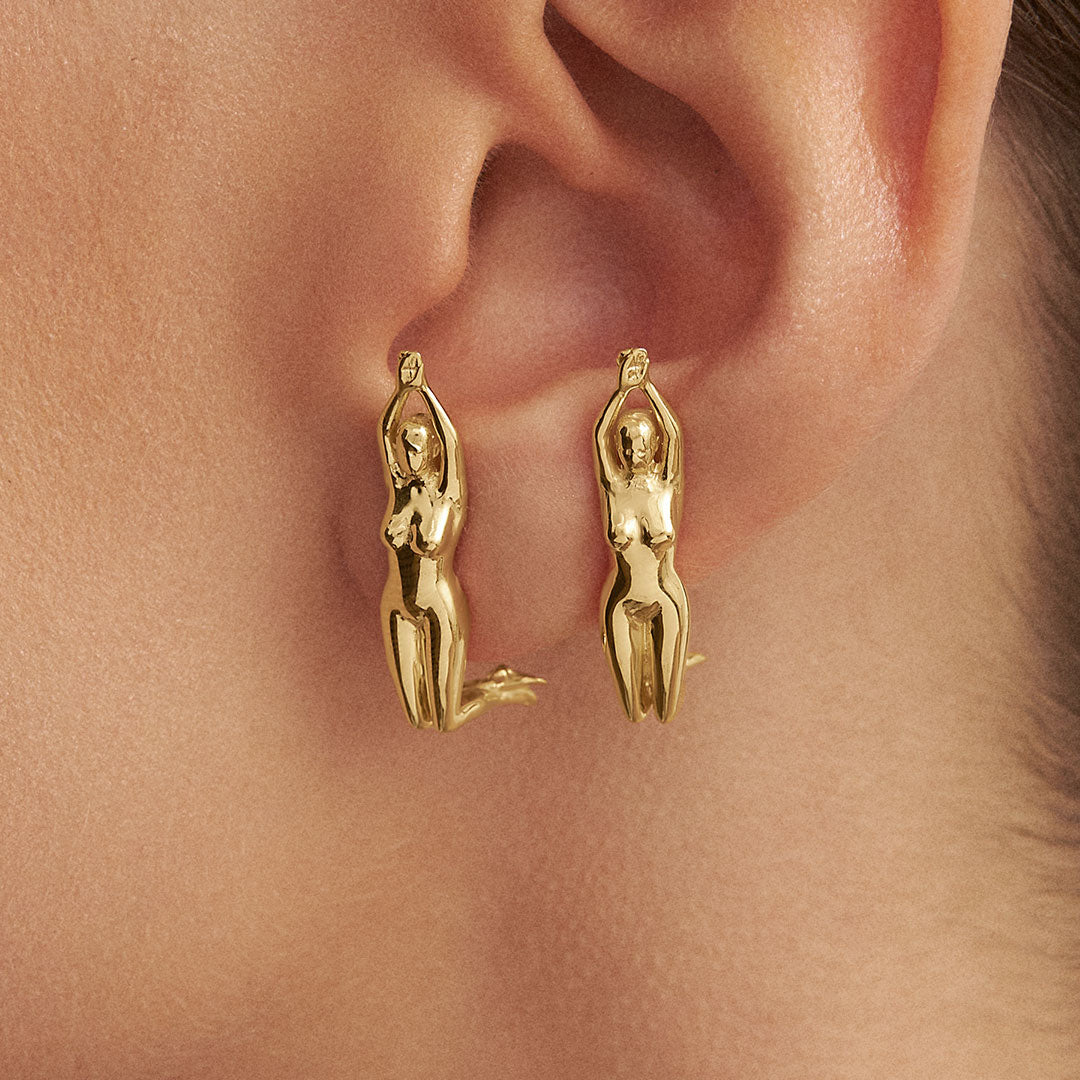 Model wearing earrings of sculptures of women in 925 silver with 18k gold plating