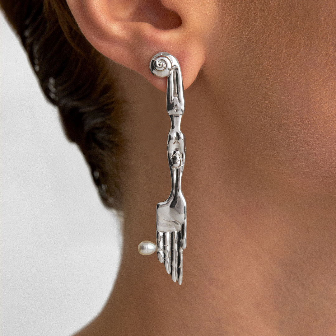Model wearing sterling silver earring in the shape of a knife with surrealist body and natural pearl