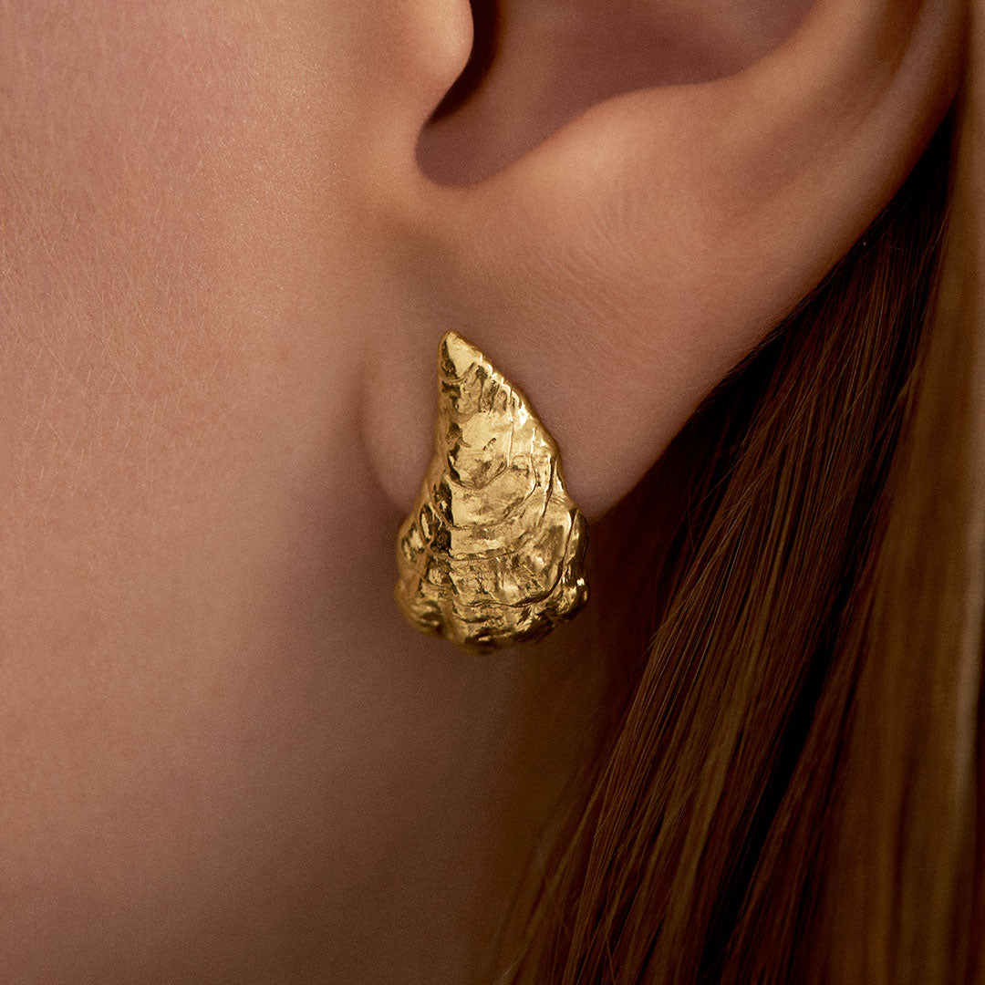 Model wearing small oyster earring in sterling silver with 18k gold plating
