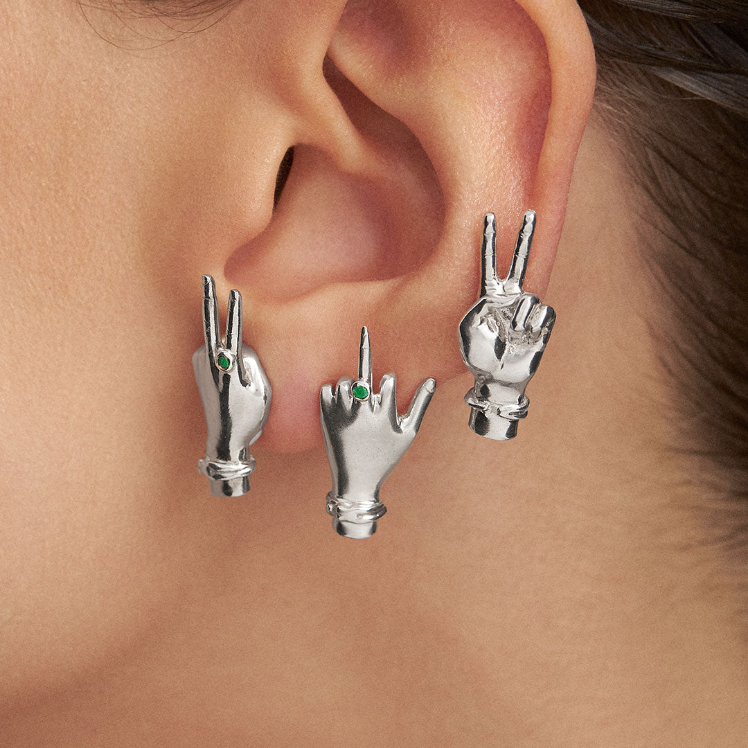 Model wearing sterling silver and emerald earrings of hands making signs