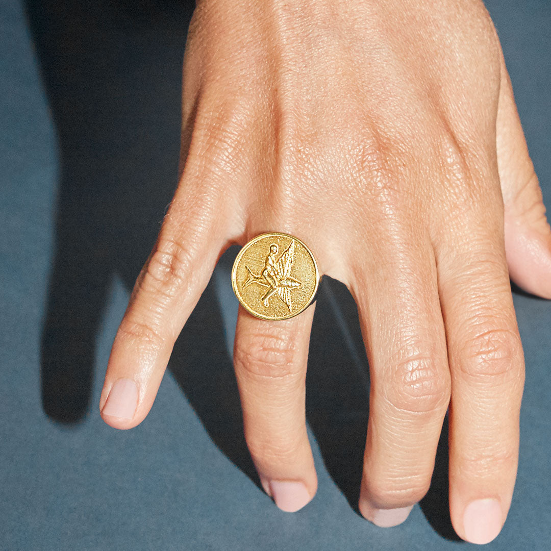 Model wearing a chevalier ring in sterling silver with 18k gold plating of a flying fish