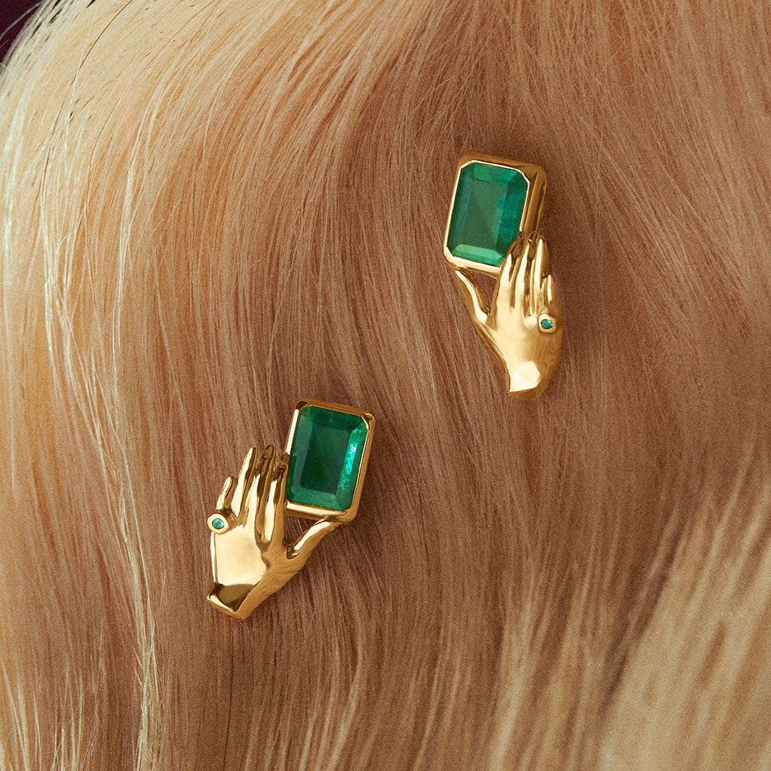 18k gold earrings of hands holding rectangular emeralds