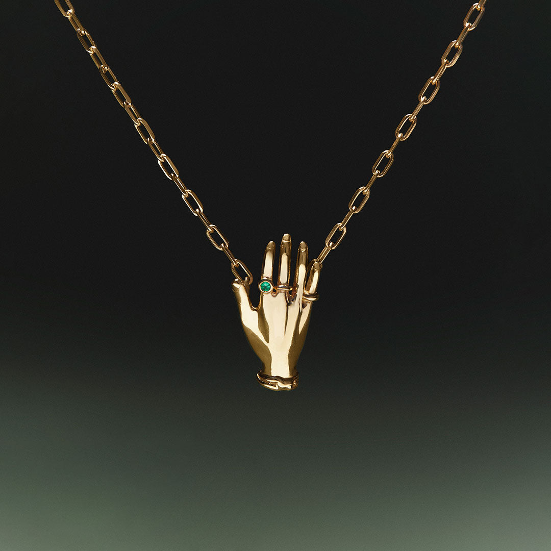 Necklace in sterling silver with 18k gold plating featuring a hand adorned with emerald