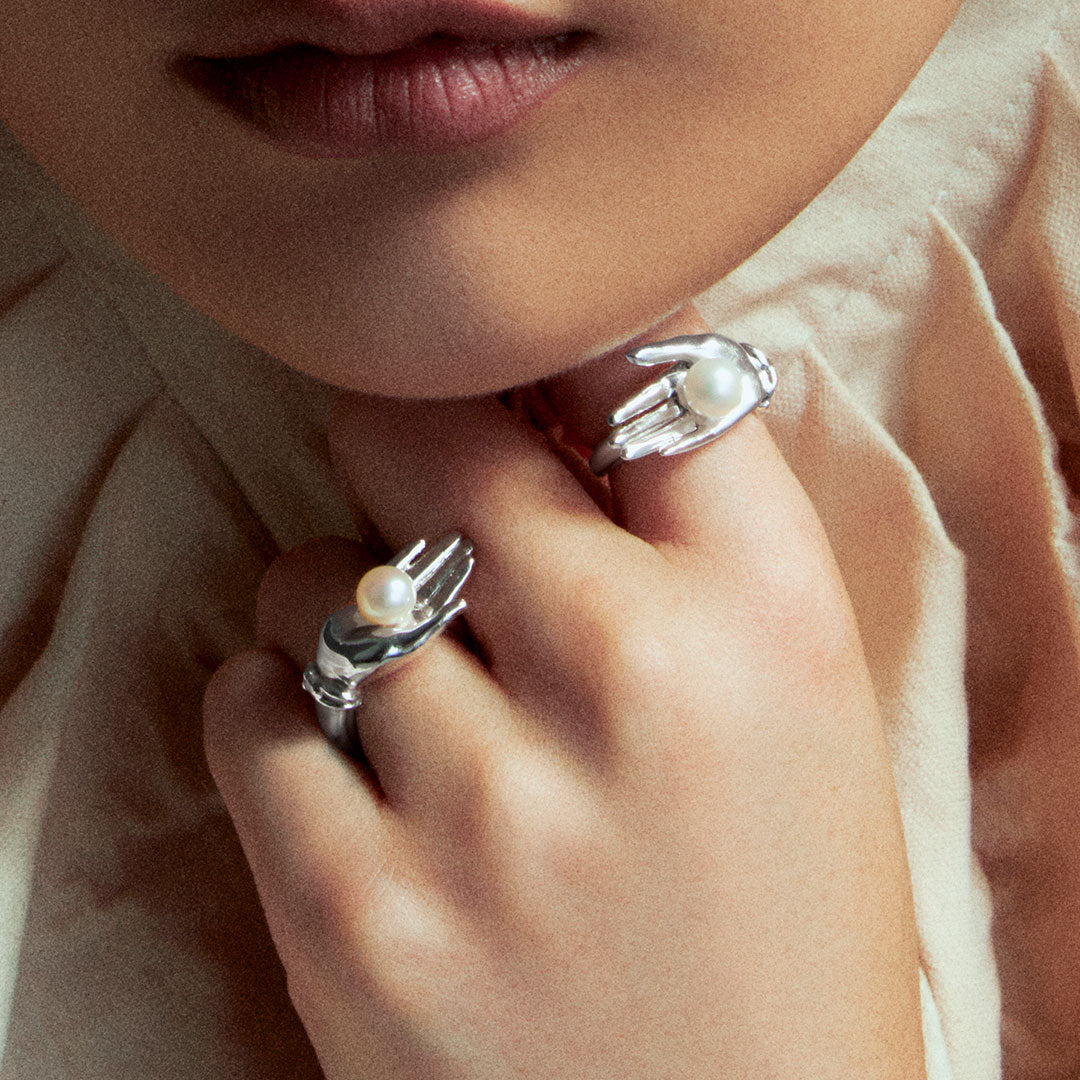Model wears hand rings in sterling silver with button pearl