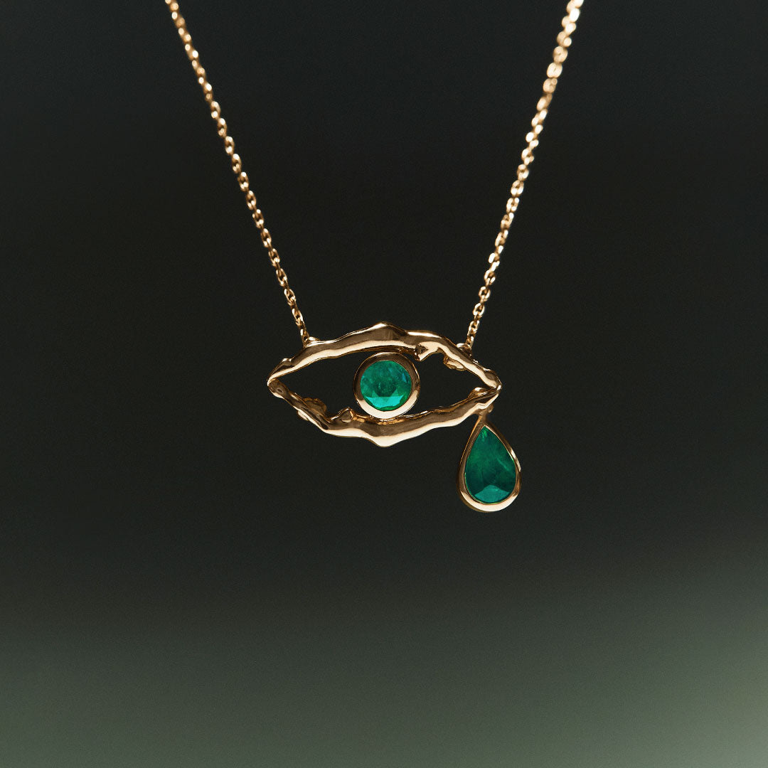 18k gold necklace of eye and female bodies adorned with emeralds