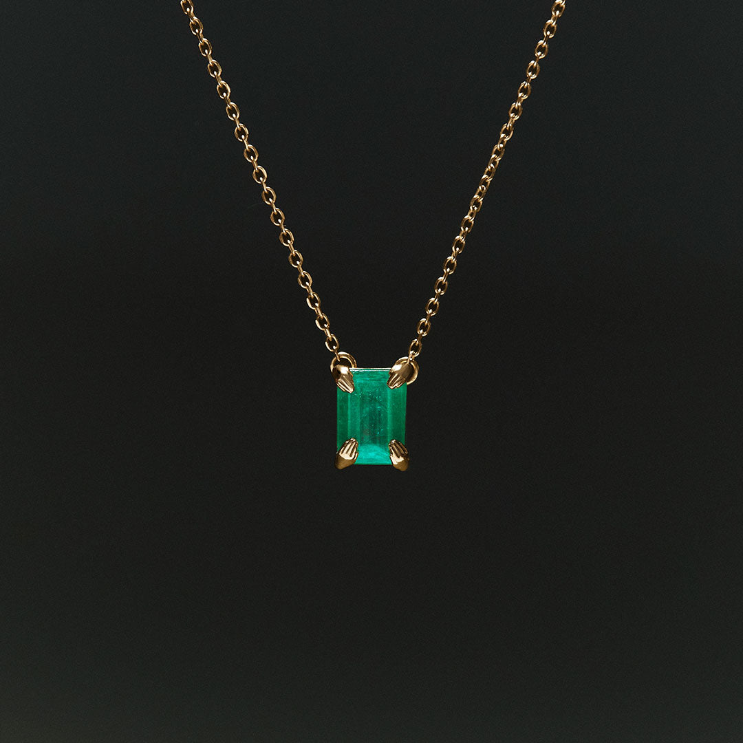 18k gold necklace with rectangular emerald and sculpted hands