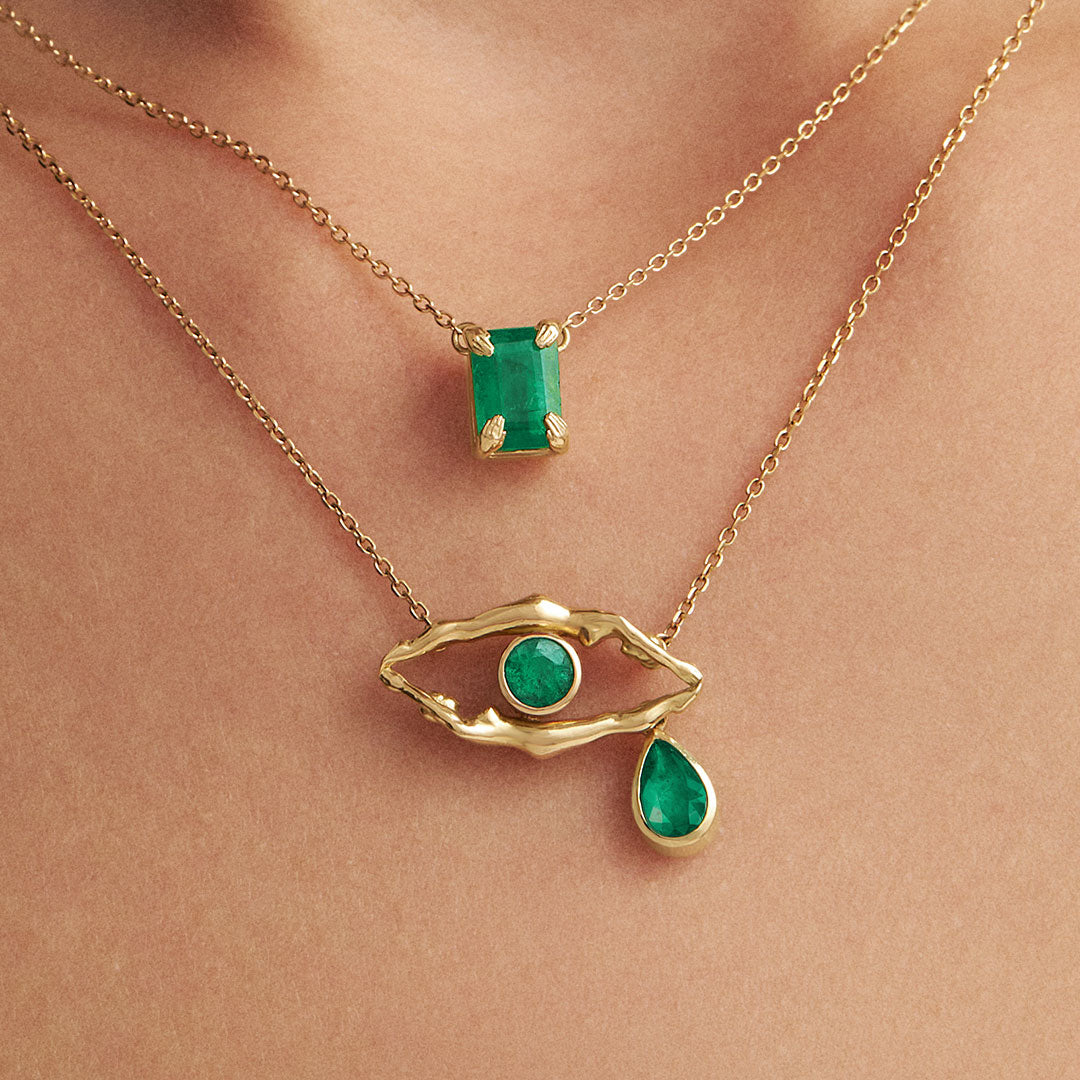 Model wearing 18k gold necklaces with emeralds