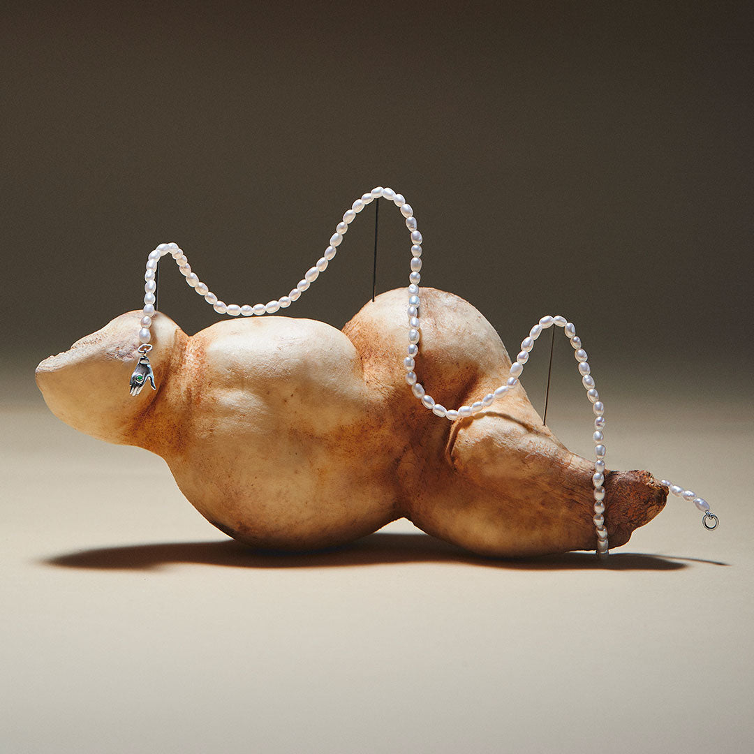 Pearl necklace with sculptural hand-shaped clasp in sterling silver adorned with emerald