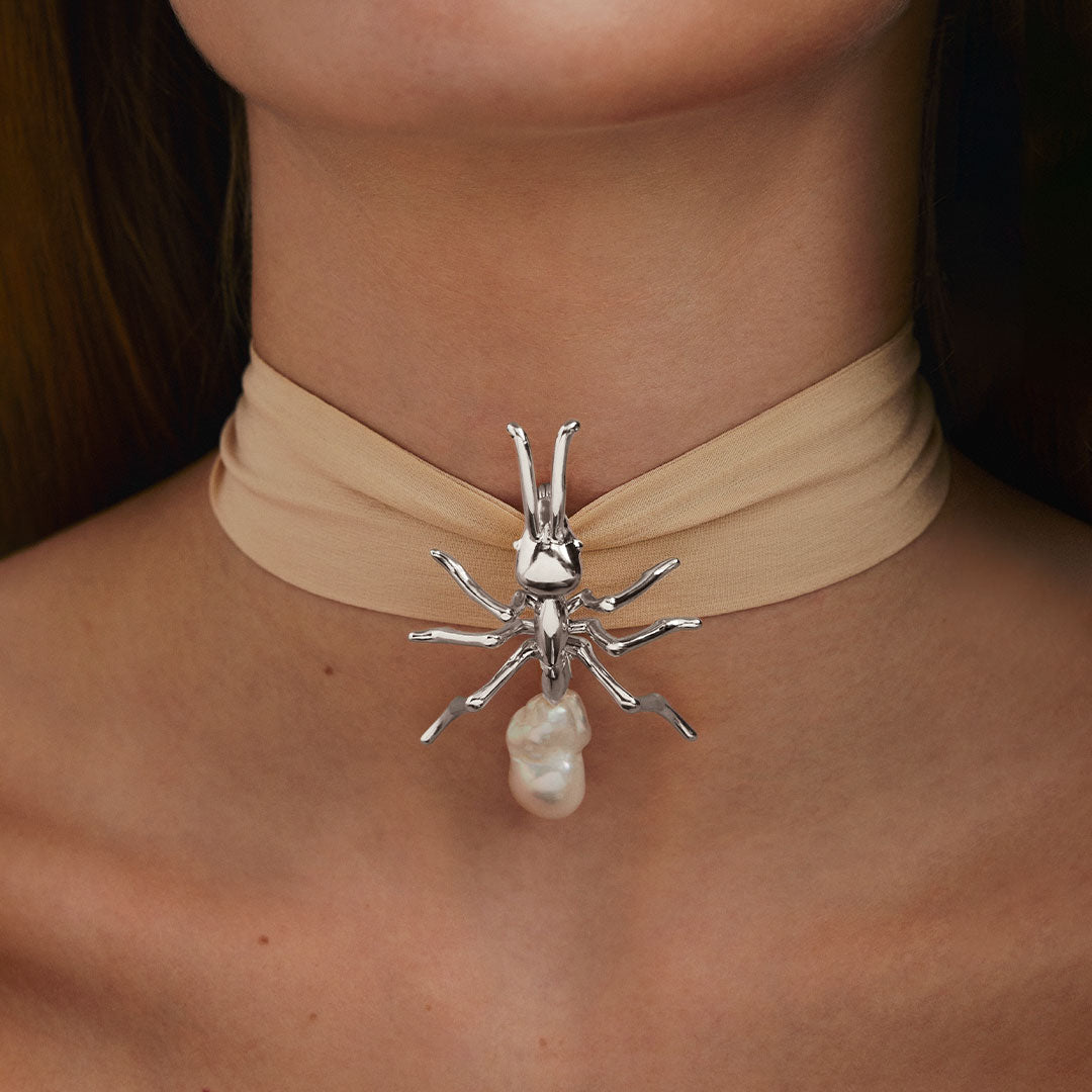 Model wearing large sterling silver ant pendant with baroque pearl on silk ribbon