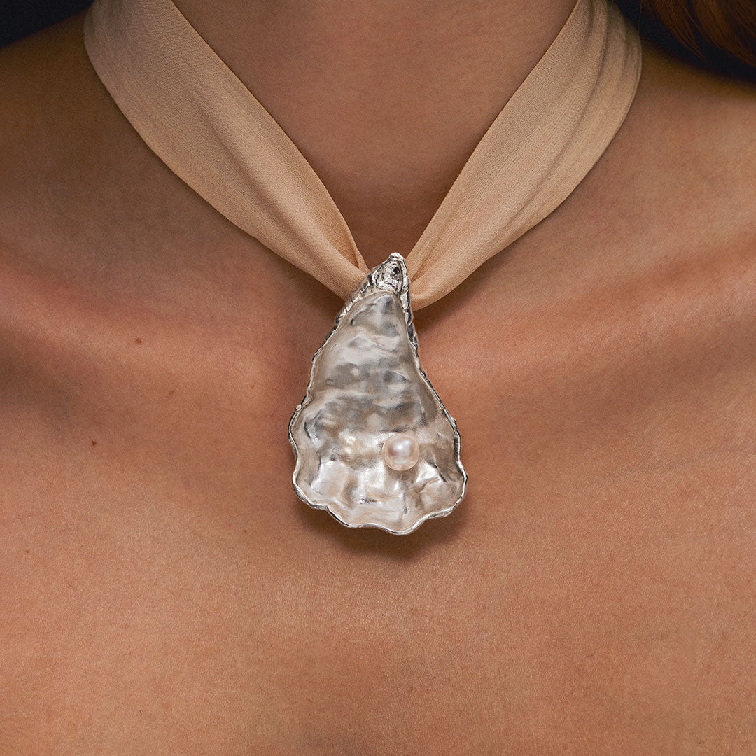 Model wearing oyster pendant in sterling silver with pearl