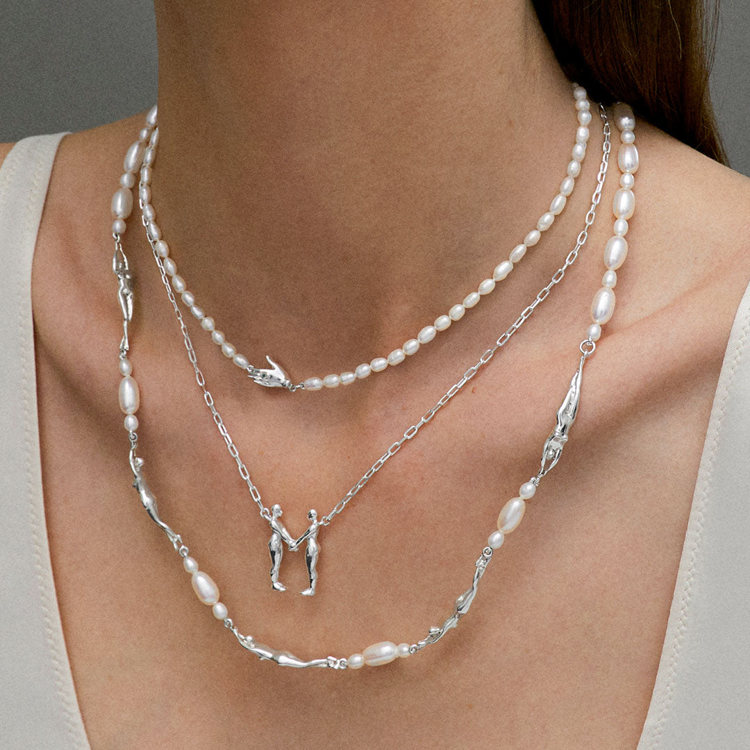Model wearing sterling silver necklaces adorned with pearls and emeralds