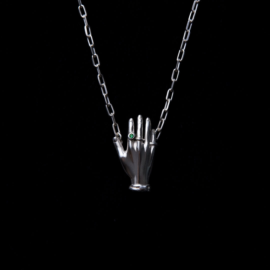 Necklace in sterling silver featuring a hand adorned with emerald
