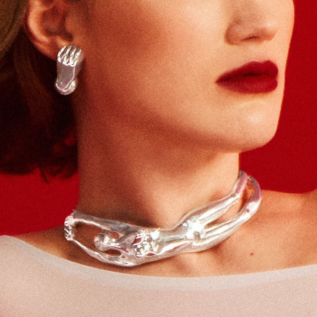 Model wearing a sculptural necklace of a female body in sterling silver