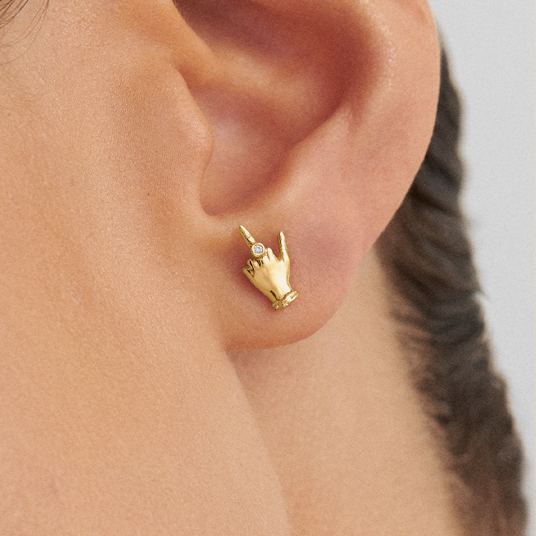 Model wearing 18k gold mini middle finger earring adorned with diamond