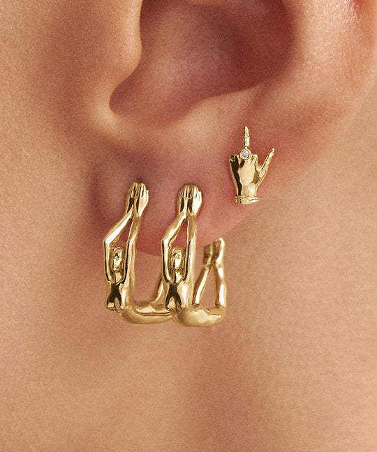 Model wearing 18k gold middle finger earrings adorned with diamond and female bodies
