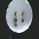 Asymmetrical 18k gold hand earrings adorned with emeralds and diamonds