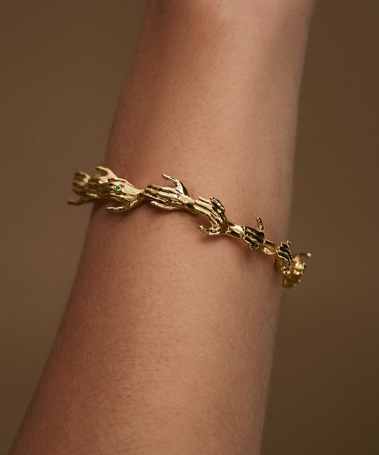 Model wearing hand-shaped bracelet in sterling silver chain with 18k gold plating