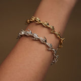 Model wearing hand-shaped bracelets in sterling silver chain with 18k gold plating and emeralds