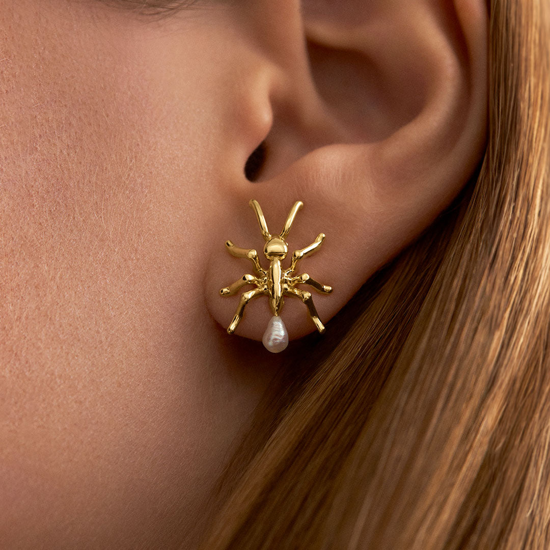 Model wearing ant earring in sterling silver with 18k gold plating and pearls