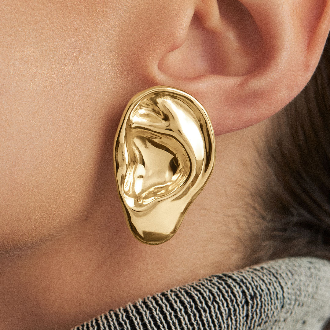 Model wearing sculpted ear earring in sterling silver with 18k gold plating