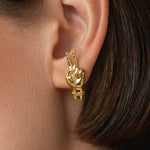 Model wearing hand-shaped earrings with peace sign in 18k gold-plated sterling silver