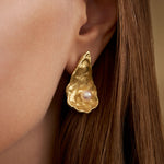 Model wearing large oyster earring in sterling silver with 18k gold plating and pearl