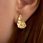 Model wearing small oyster earring in sterling silver with 18k gold plating and pearl