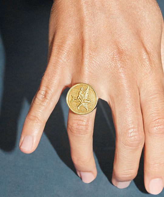 Model wearing a chevalier ring in sterling silver with 18k gold plating of a flying fish