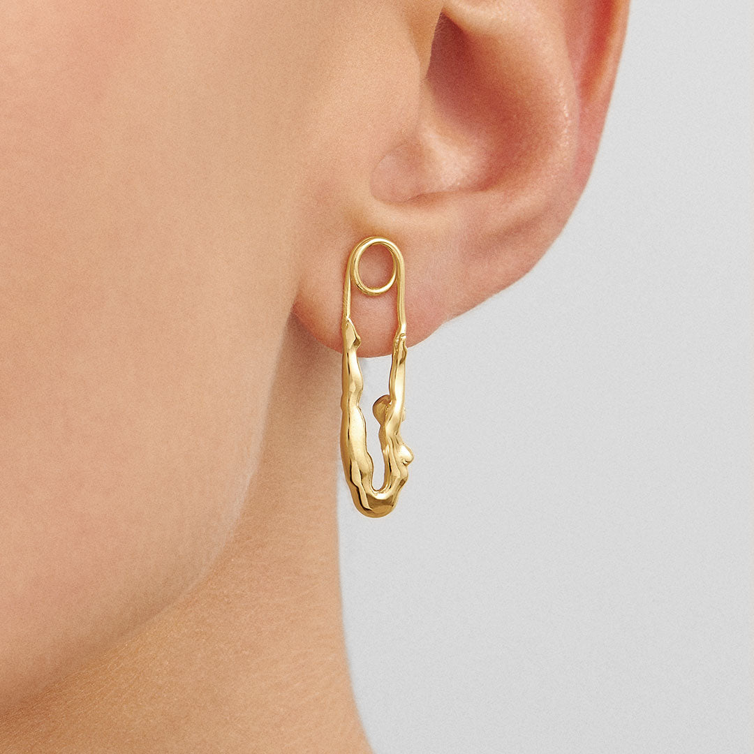 Model wearing sterling silver earring with 18k gold plating featuring a safety pin and female body