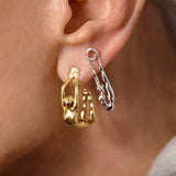 Model wearing sterling silver earrings with 18k gold plating featuring hoop and safety pin with female bodies
