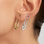 Model wearing sterling silver earrings with 18k gold plating featuring safety pins and female bodies