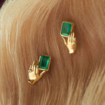 18k gold earrings of hands holding rectangular emeralds