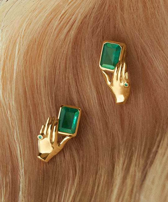 18k gold earrings of hands holding rectangular emeralds