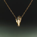 Necklace in sterling silver with 18k gold plating featuring a hand adorned with emerald
