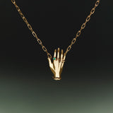 Necklace in sterling silver with 18k gold plating featuring a hand adorned with emerald