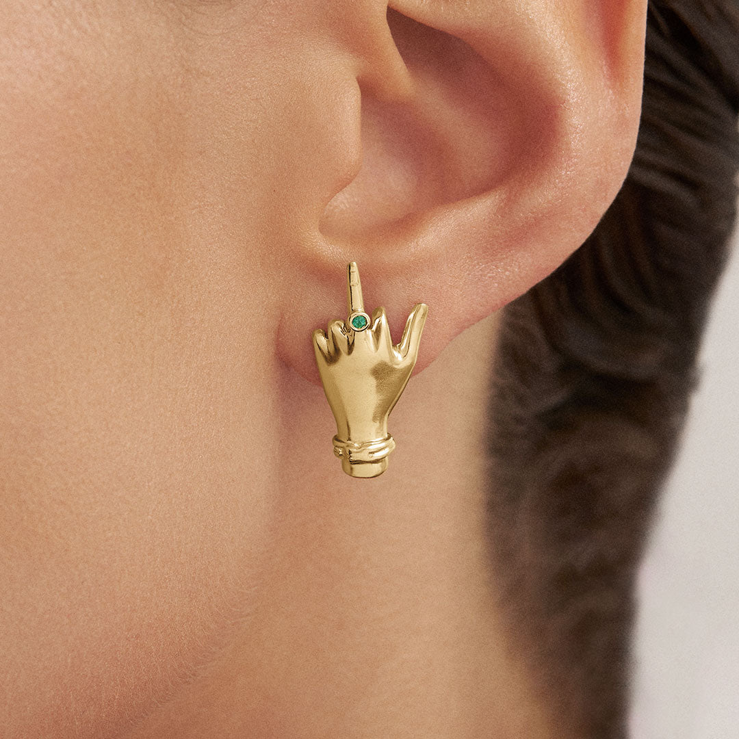 Model wearing sterling silver middle finger earring with 18k gold plating and emerald