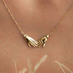 Model wearing 18k gold necklace of hands adorned with diamond