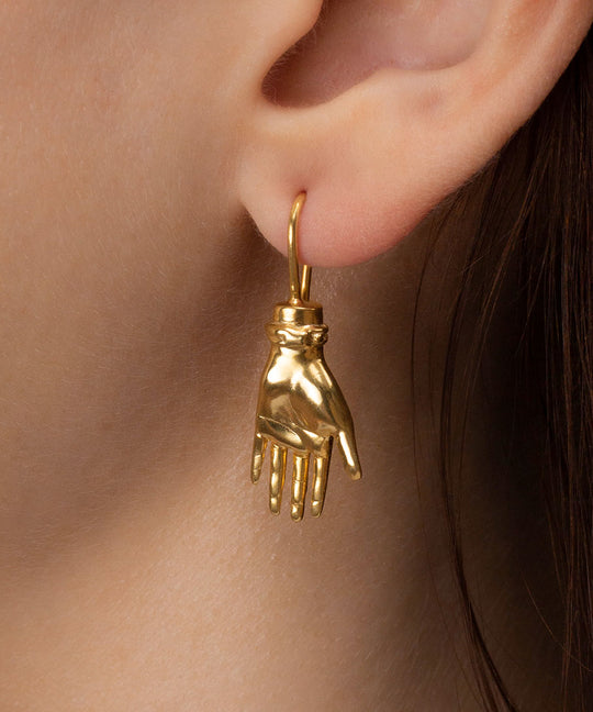 Model wearing a palm-shaped earring in sterling silver with 18k gold plating