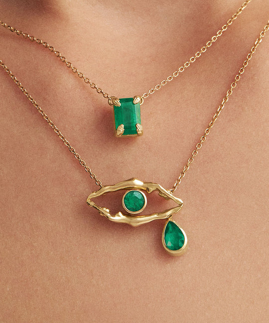 Model wearing 18k gold necklaces with emeralds