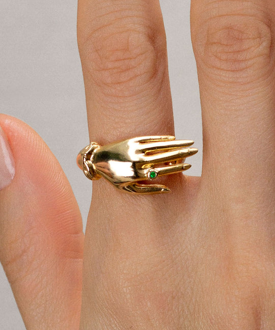 Model wearing a sterling silver ring with 18k gold plating of a hand with an emerald