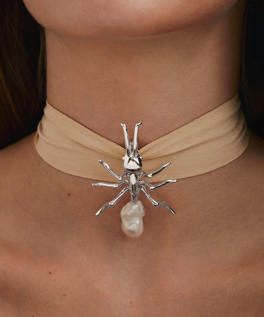 Model wearing large sterling silver ant pendant with baroque pearl on silk ribbon