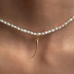 Model wearing 18k gold eyelash pendant on a pearl necklace