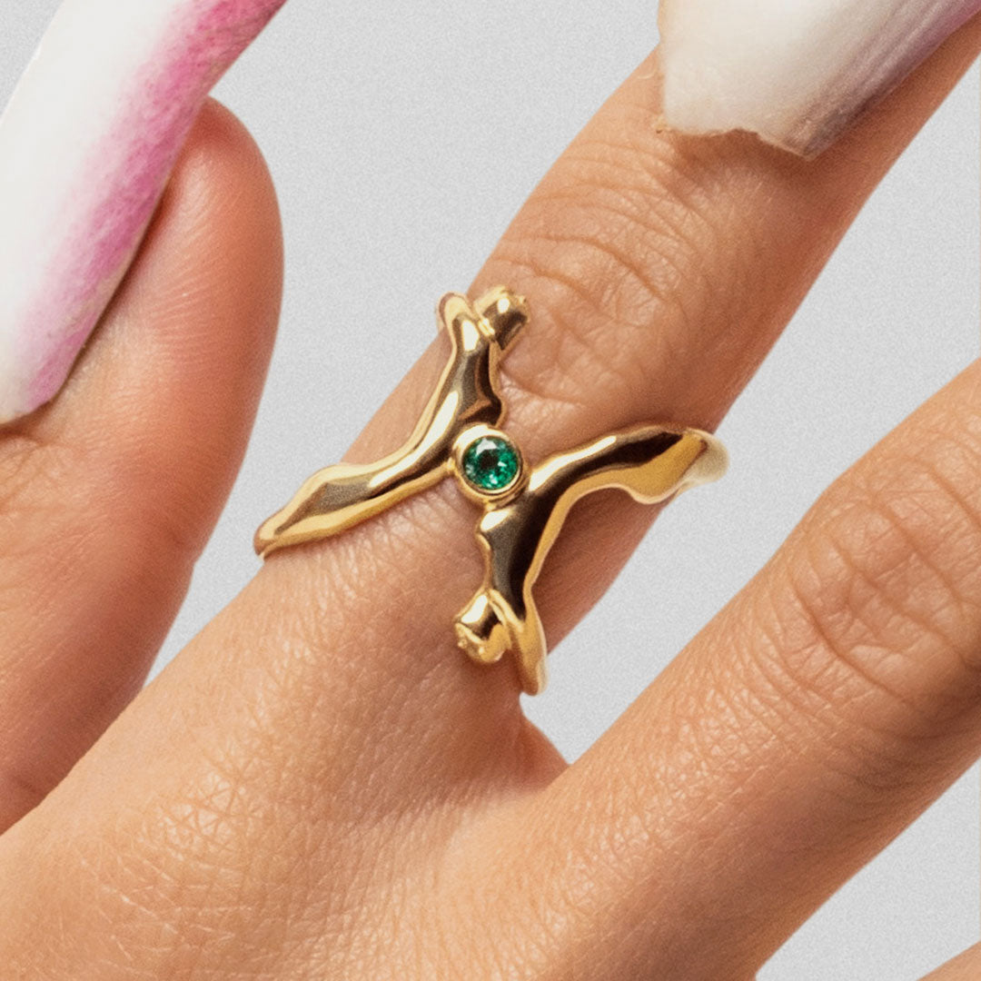 Model wearing 18k gold ring of bodies adorned with emerald