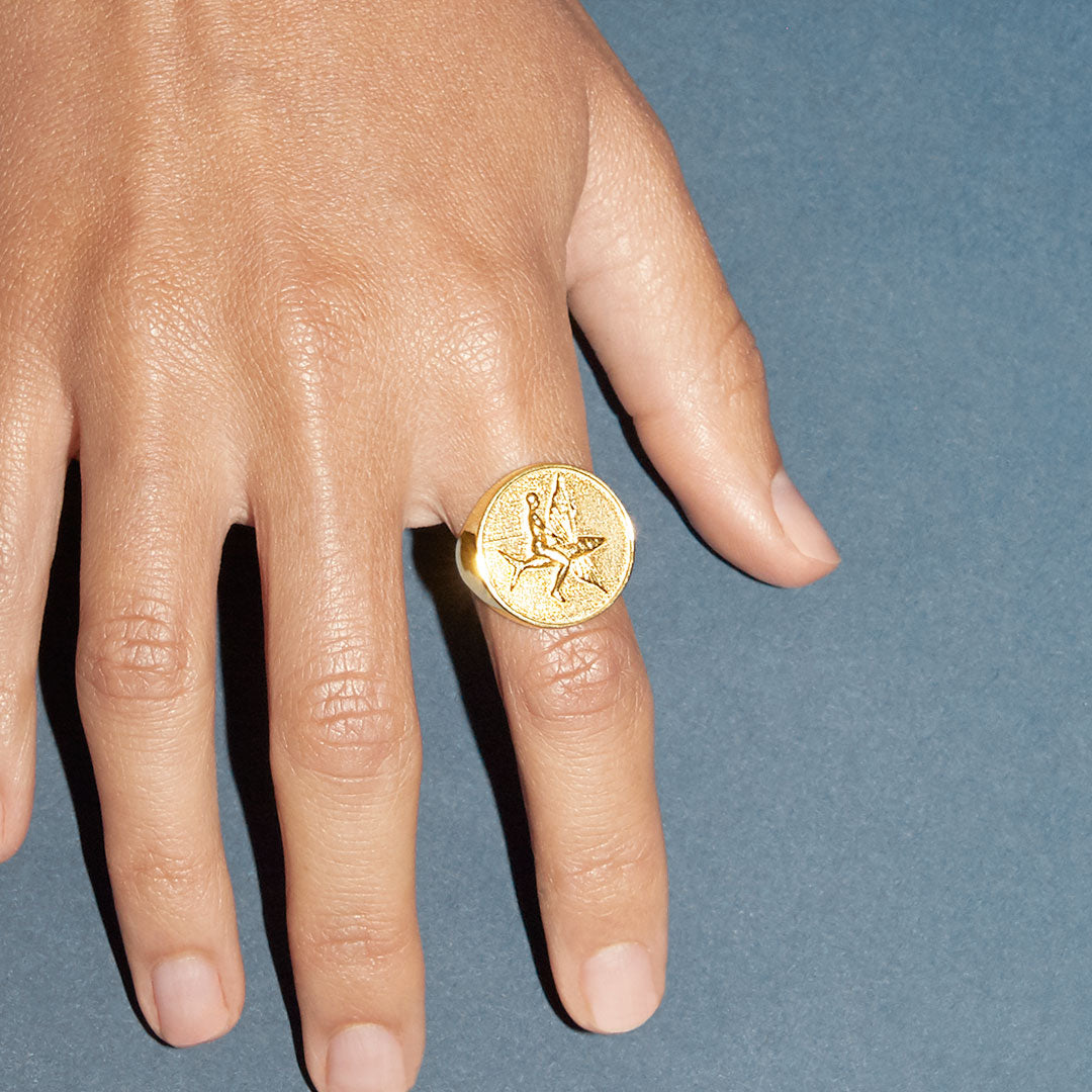 Model wearing a sterling silver ring with 18k gold plating of a flying fish