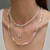 Model wearing sterling silver necklaces adorned with pearls and emeralds