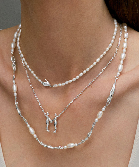 Model wearing sterling silver necklaces adorned with pearls and emeralds