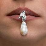 Model wearing hand-shaped earring in sterling silver with emerald and baroque pearl